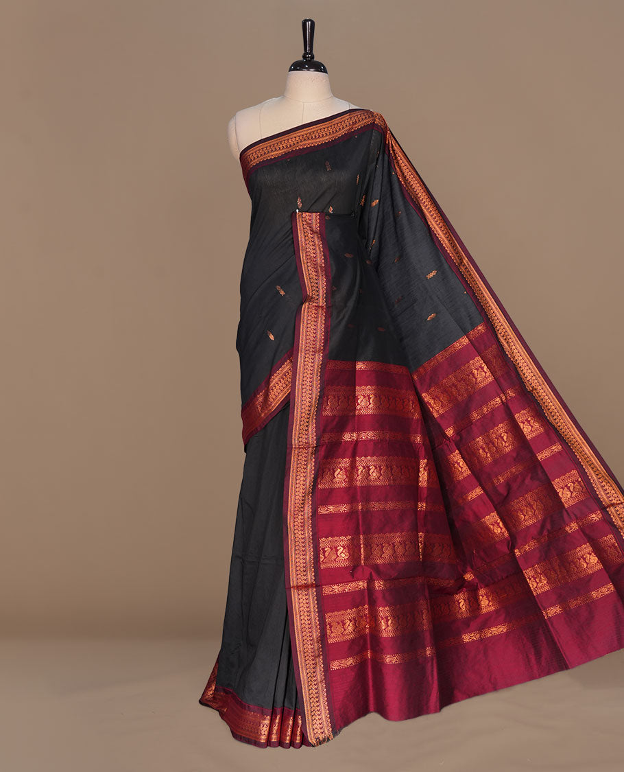 Black colour kalyani cotton saree featuring gold zari motifs on body, complemented by contrast maroon color with copper zari pattern border , paired with matching blouse piece.