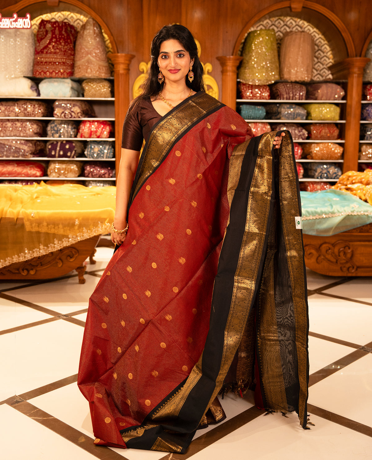 Maroon with Black colour Chettinad cotton saree featuring Gold zari strips with peacock motifs on body, complemented by contrast colour border with zari design & grand pallu, comes with matching blouse piece.