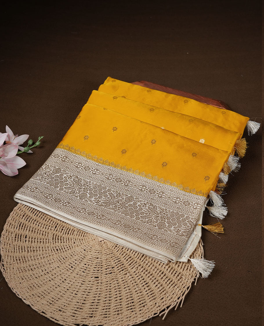 Yellow colour banaras satin crepe saree featuring gold zari motifs on body, with contrast cream colour border with gold zari pattern and paired with matching blouse.
