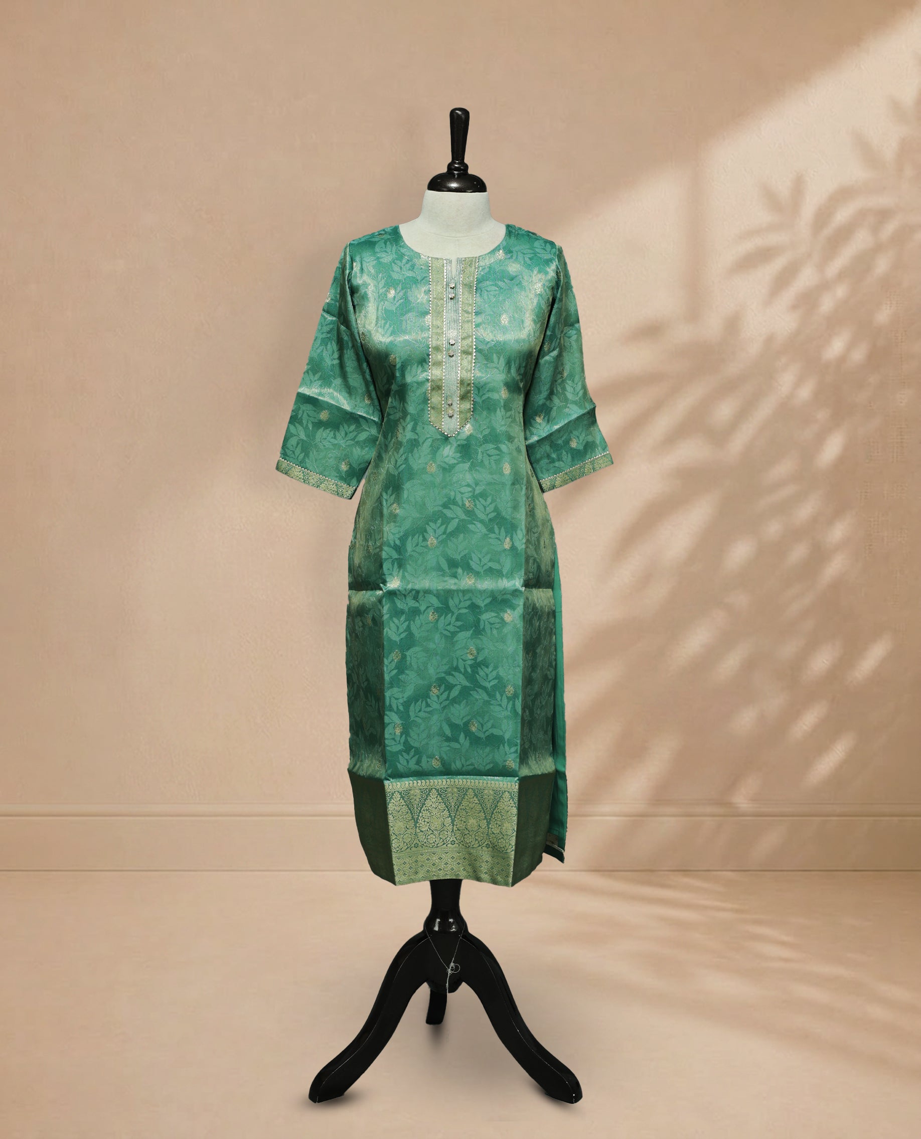 Green colour tissue Kurti featuring a delicate floral leaf pattern with subtle gold motifs, a round neckline adorned with intricate thread and Stone detailing, and 3/4 sleeves finished with matching embroidered borders.