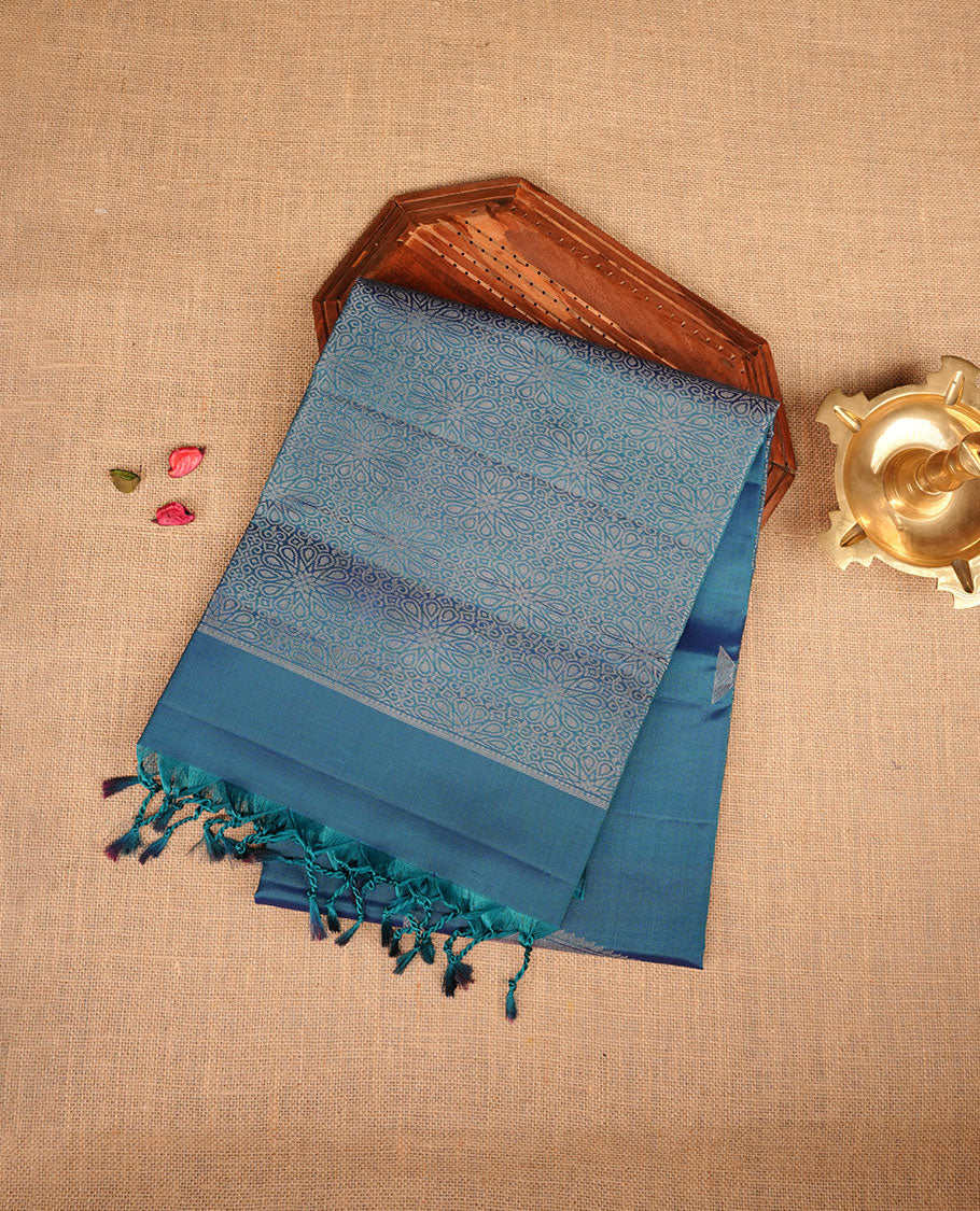 Peacock colour soft silk saree featuring silver zari motifs on body, complemented by self colour with traditional border with tassel at pallu, paired with matching blouse piece.