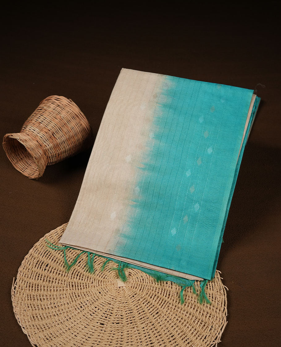 Cream & aqua dye pattern colour semi jute saree highlighting white stripped body, without border and paired with matching blouse.