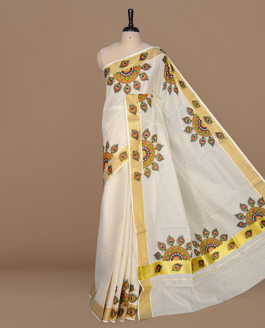 Off white color kerala cotton saree featuring gold zari check on body, complemented by, gold zari with peacock leaf printed border, paired with matching blouse piece.