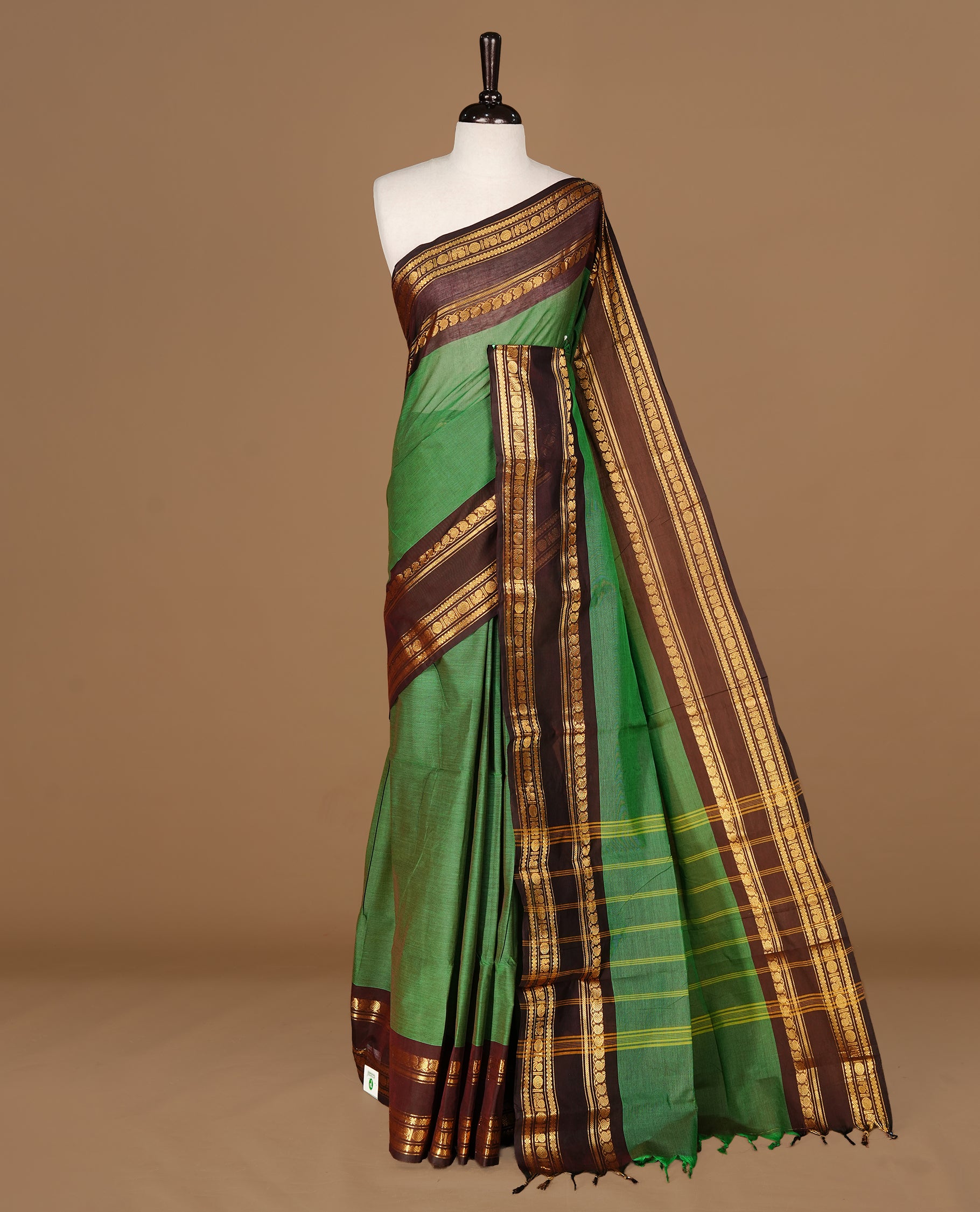 Green colour Chettinad cotton saree featuring Elegant plain body, complemented by contrast Chocolate Brown colour with gold zari border, paired with matching blouse piece.