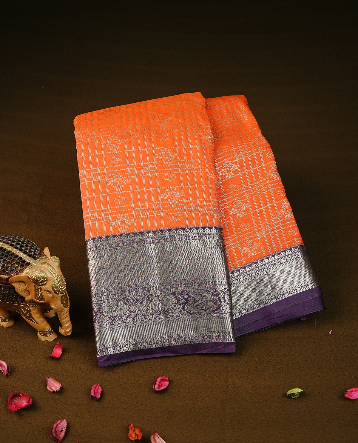 orange colour semi wedding silk saree featuring light gold zari checks with florals on body, contrast purple colour with traditional border on body, rich pallu comes with matching blouse piece