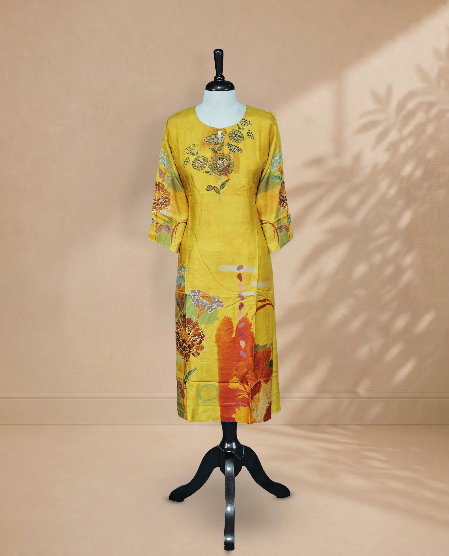 Mustard yellow Kurti featuring floral on the Body , a round neckline with a Floral Embroidery Work,A vibrant floral printed 3/4 sleeves, and a colourful floral and abstract print along the lower portion.