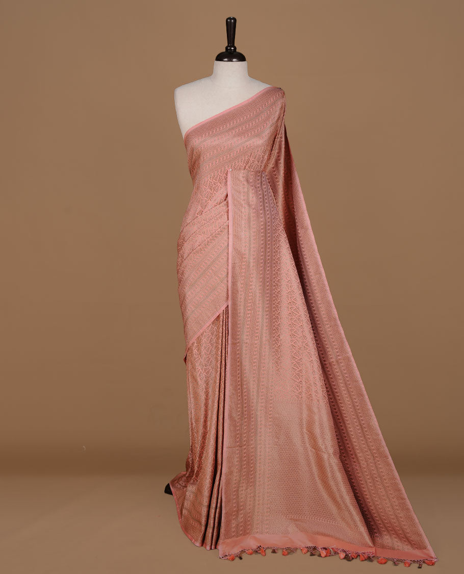 Peach colour Semi Banaras Katan saree featuring Antique zari Floral pattern on body, complemented by self colour zari border, paired with matching blouse piece.