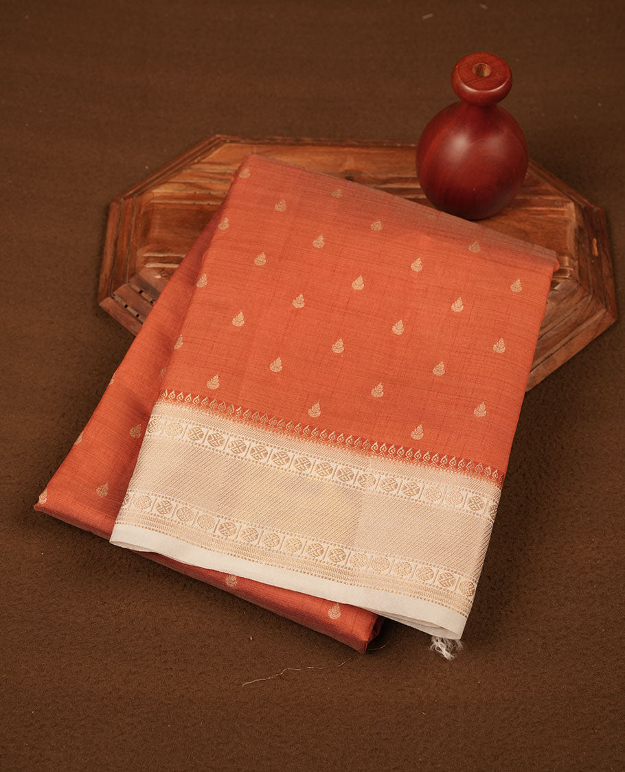 Orange colour tussar saree featuring litte gold zari motifs on body, contrast cream colour border and pallu with zari woven design, comes with matching blouse piece.