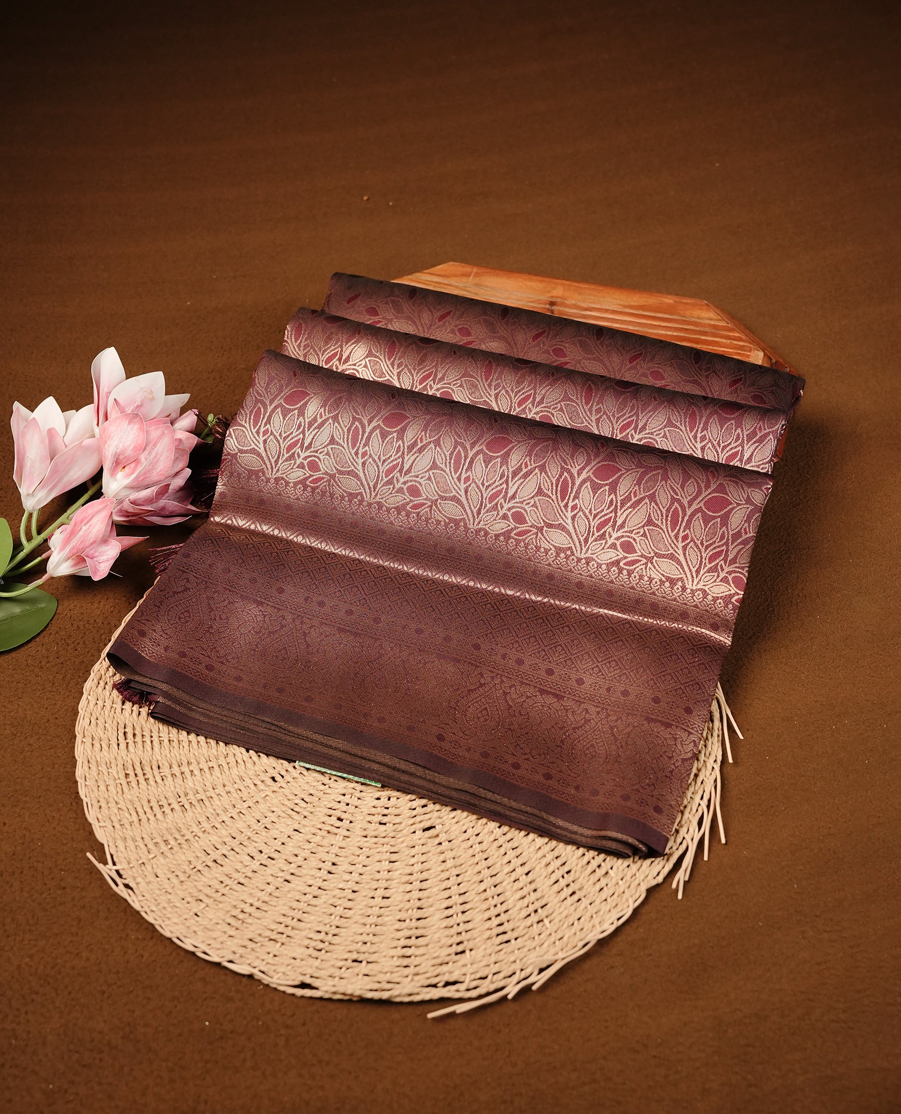 Maroon Colour Softie Silk Saree Featuring An All Over Gold Woven Leaf Pattern, Finished With A Matching Border Adorned With Intricate Paisley And Floral Motifs, Paired With A Matching Blouse Piece.