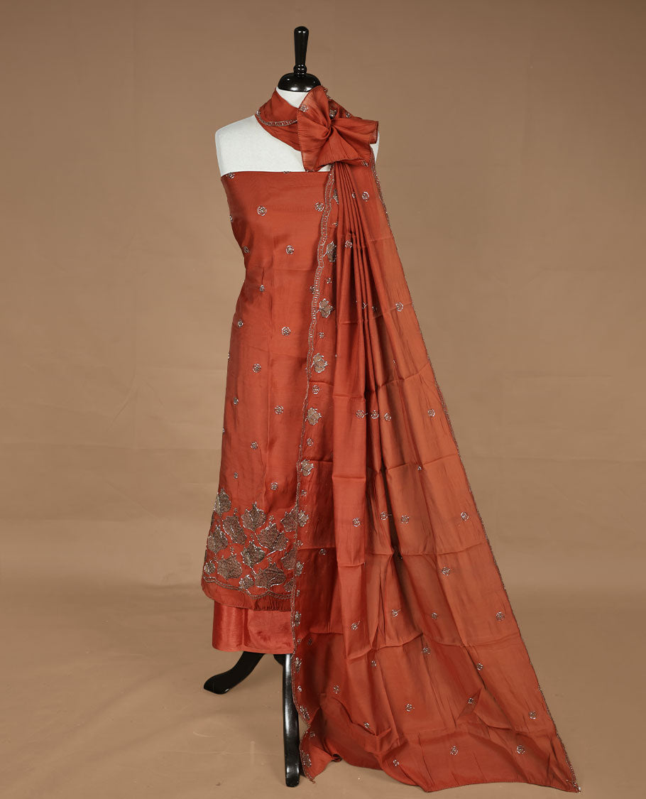 Brick orange colour churidar materal featuring floral cut beats and thread work on body, paired with matching bottom and dupatta.
