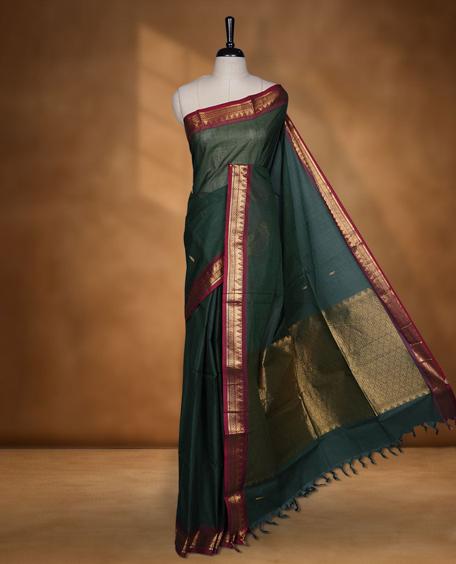 Dark green colour chettinad cotton saree featuring gold zari motifs on body, contrast Red colour with traditional gold zari border paired with matching blouse.