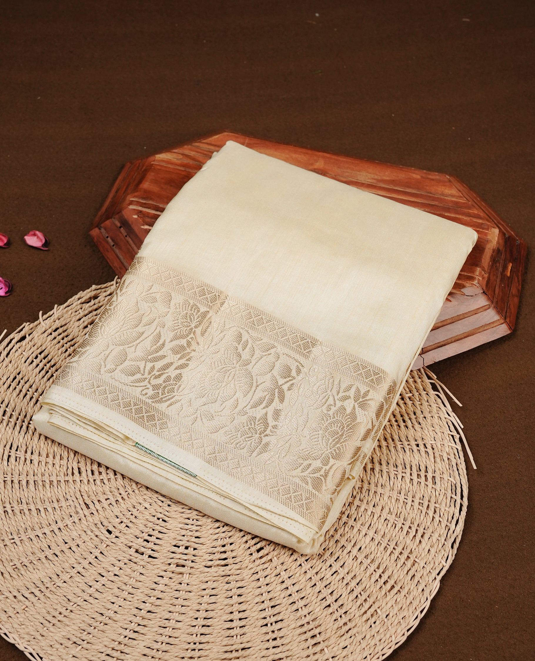 Cream colour semi Tussar silk saree featuring an elegant plain body, complemented by a self colour border adorned with traditional gold zari floral kodi patterns. Comes paired with a matching blouse piece.