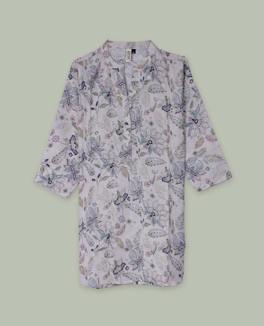White tunic top with pastel floral and paisley print, band collar, pintuck-detailed front with half button placket, and three-quarter sleeves.