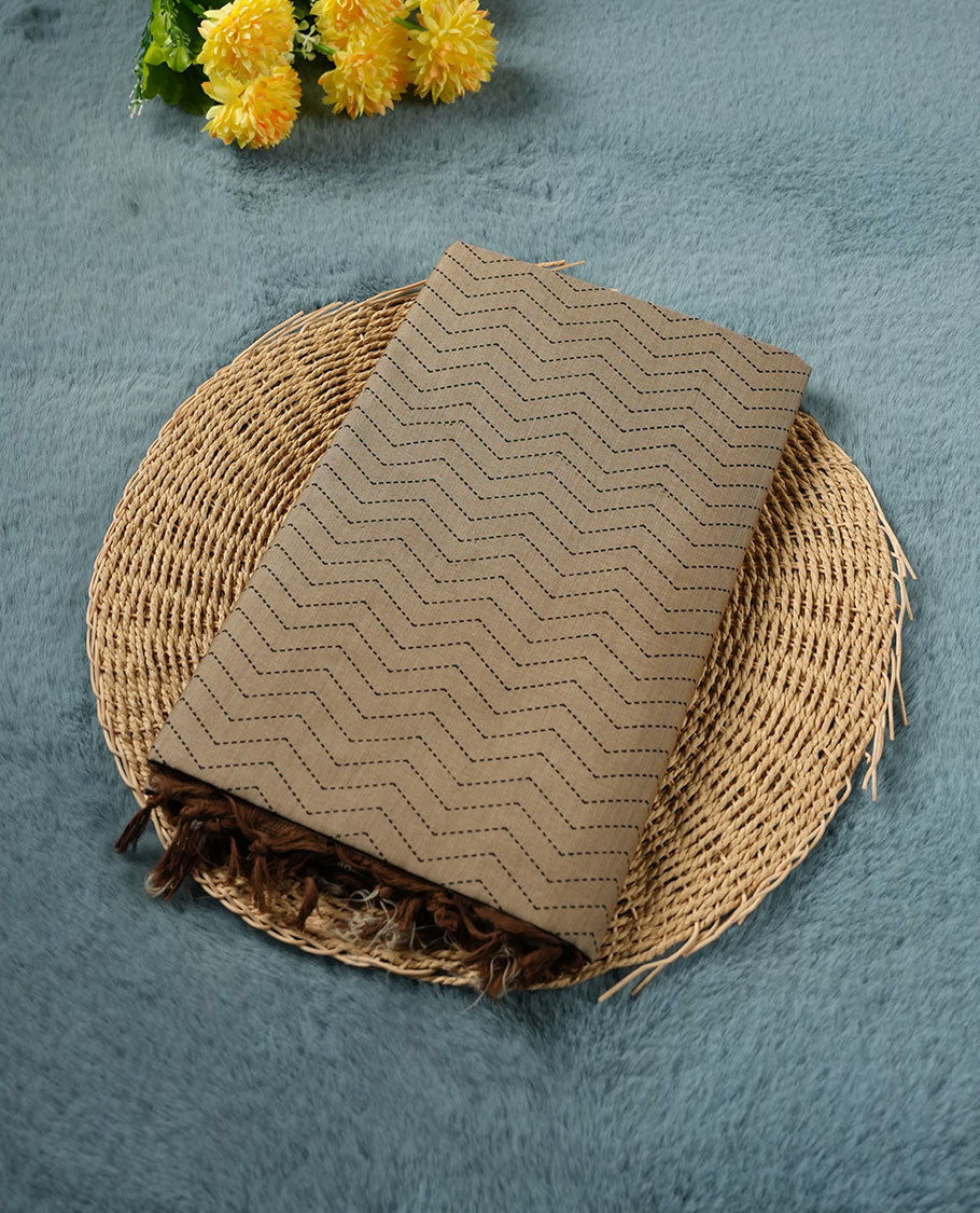 Dark Beige colour poly cotton saree with black zigzag line pattern on the body, paired with a matching pallu featuring black chevron lines and panelled floral‑paisley design, and a coordinated all‑over floral paisley patch‑style printed blouse piece.