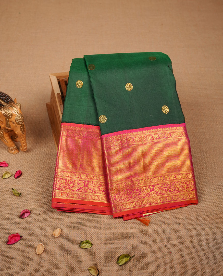 Bottle green colour pure traditional Kancheepuram silk saree adorned with gold zari motifs across the body, featuring elegant contrast orange traditional borders, beautifully paired with a matching blouse piece.