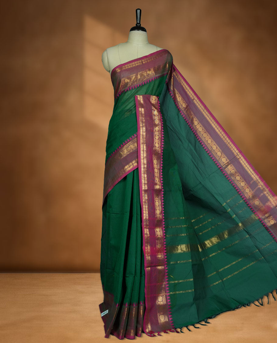 Dark green colour chettinad cotton saree featuring Elegant plain body, contrast Meganta colour border with gold zari chakra and temple border, pallu and paired with matching blouse.