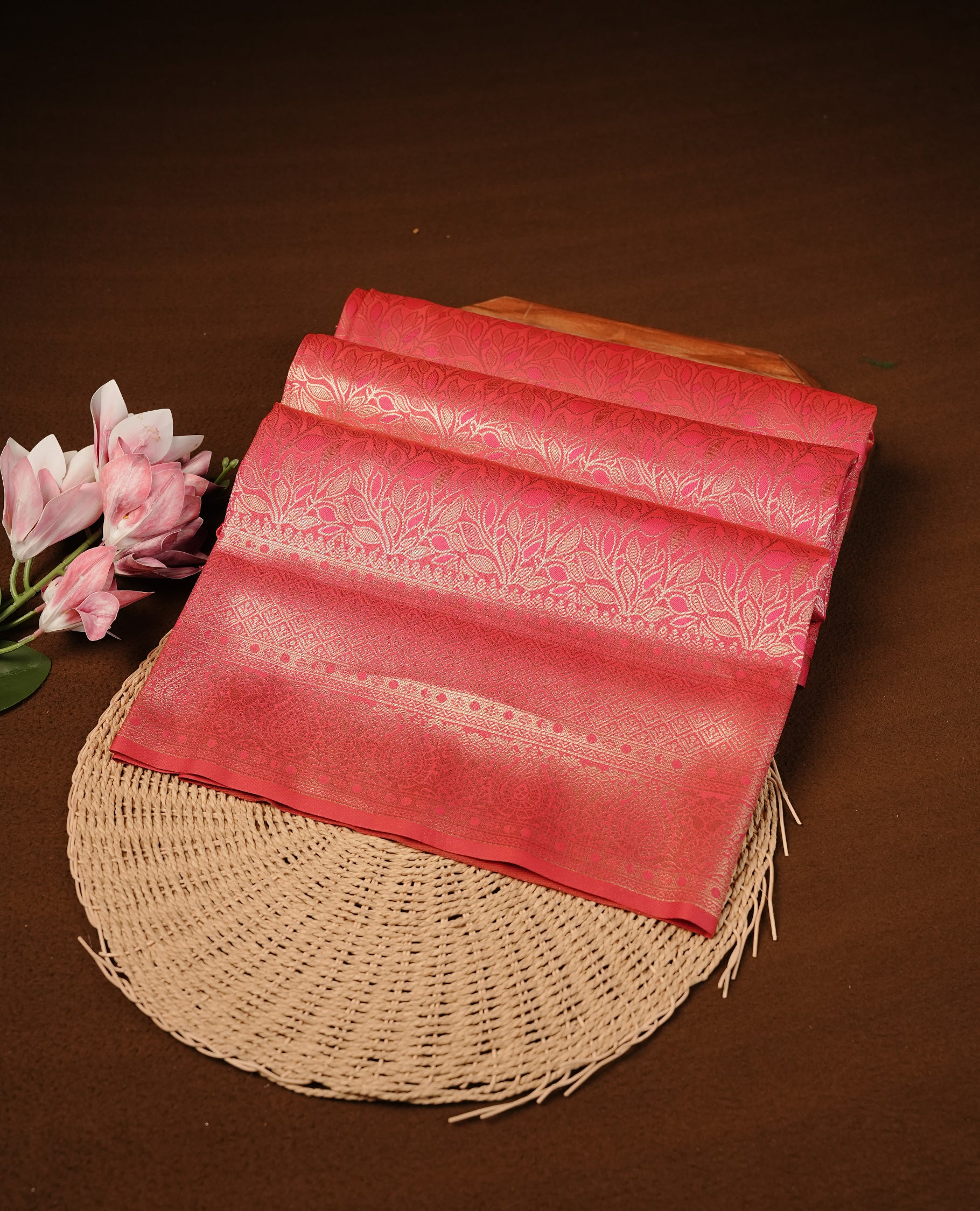 Rani Pink Colour Softie Silk Saree Featuring An All Over Gold Woven Leaf Pattern, Finished With A Matching Border Adorned With Intricate Paisley And Floral Motifs, Paired With A Matching Blouse Piece.