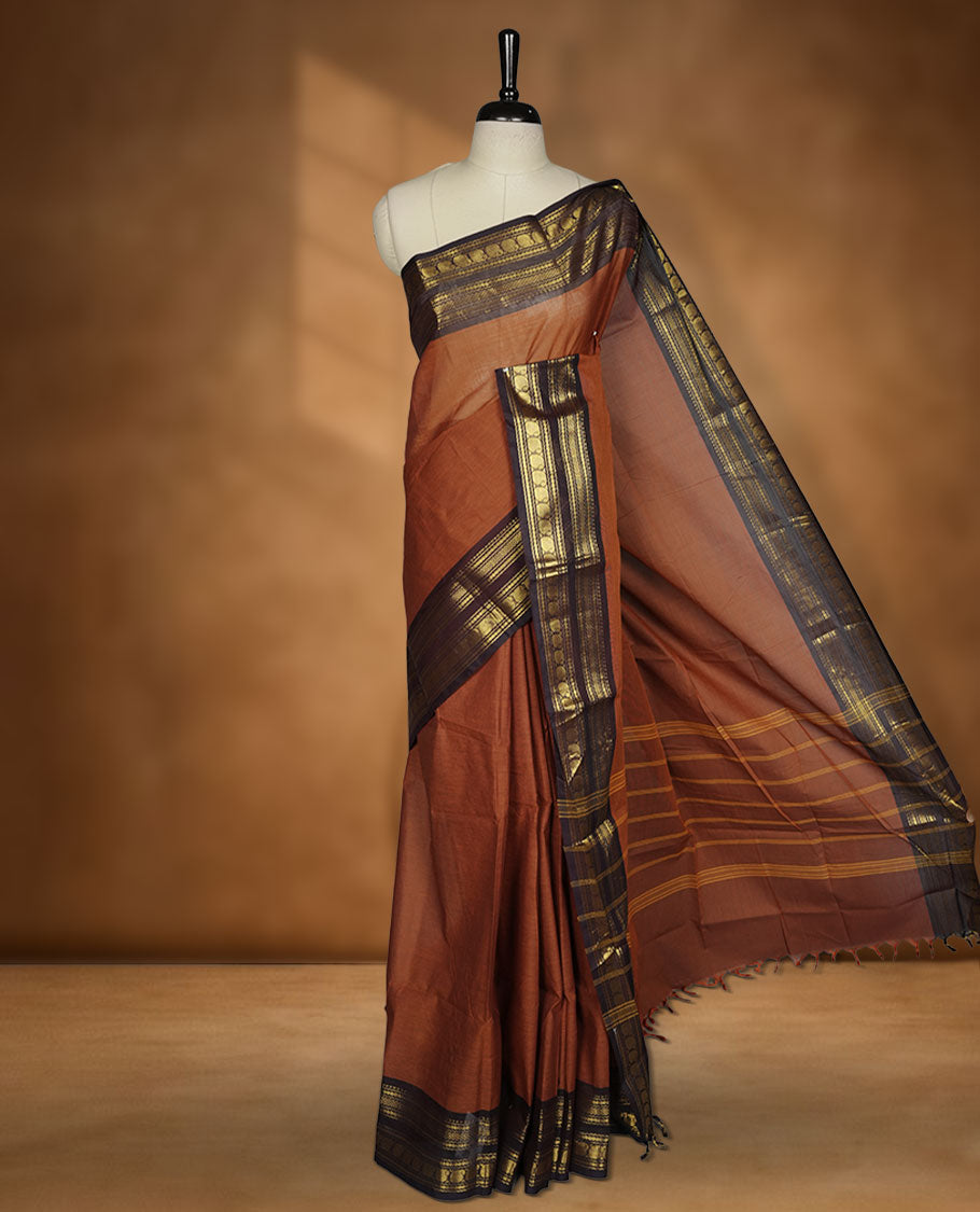 Brown colour chettinad cotton saree featuring plain body, contrast Deep purple colour with traditional gold zari border paired with matching blouse.