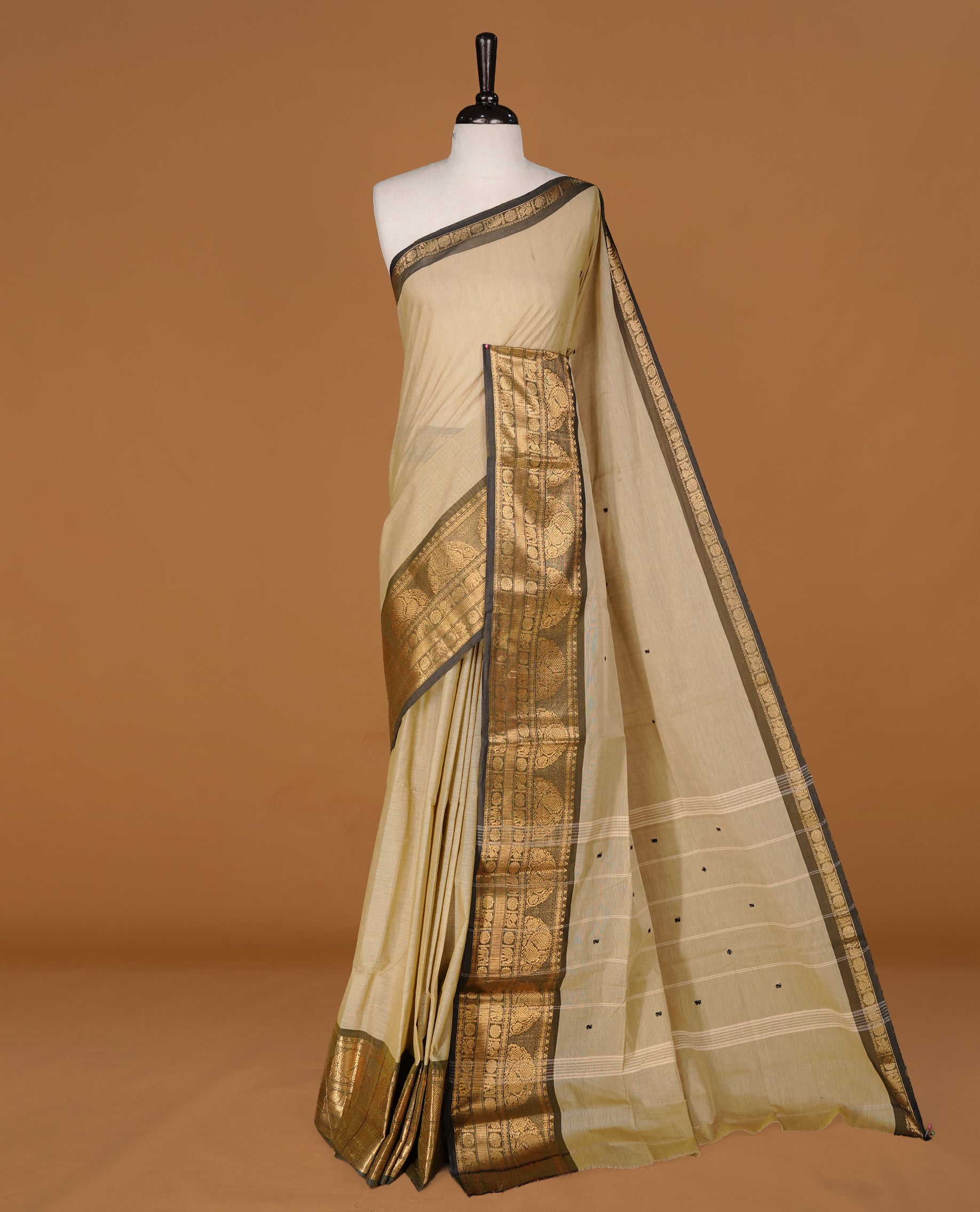 Greyish cream colour Chettinad cotton saree featuring motifs body, complemented by contrast Black colour with gold zari border, paired with matching blouse piece.