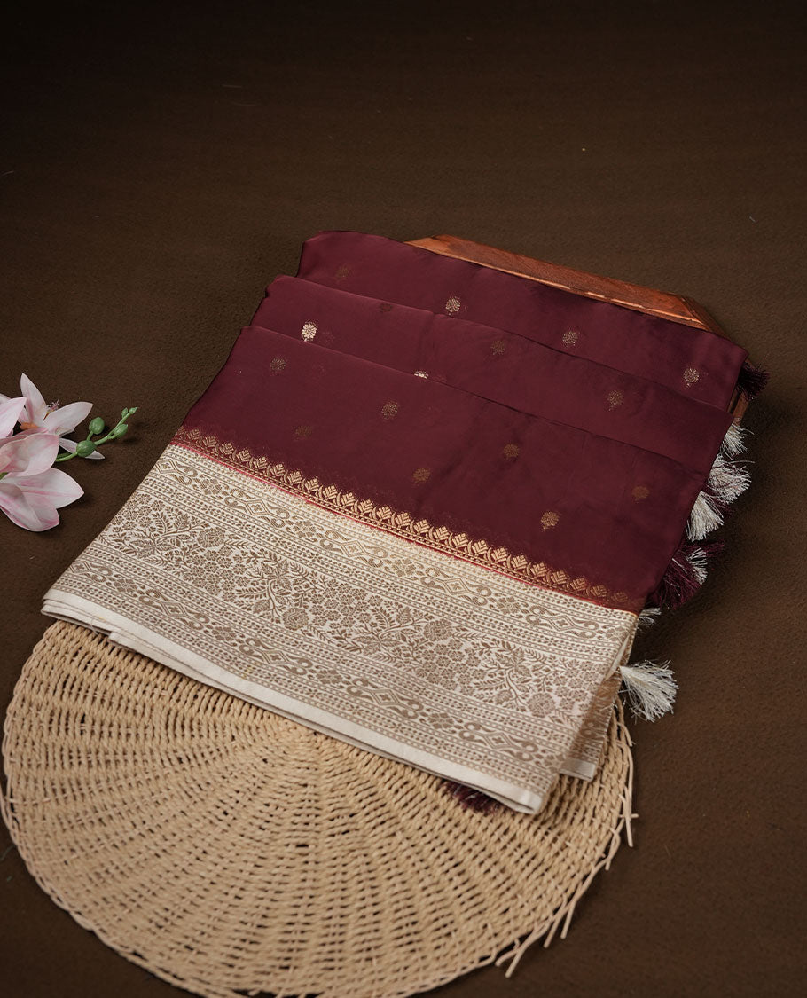 Chocolate brown colour banaras satin crepe saree featuring gold zari motifs on body, with contrast cream colour border with gold zari pattern and paired with matching blouse.