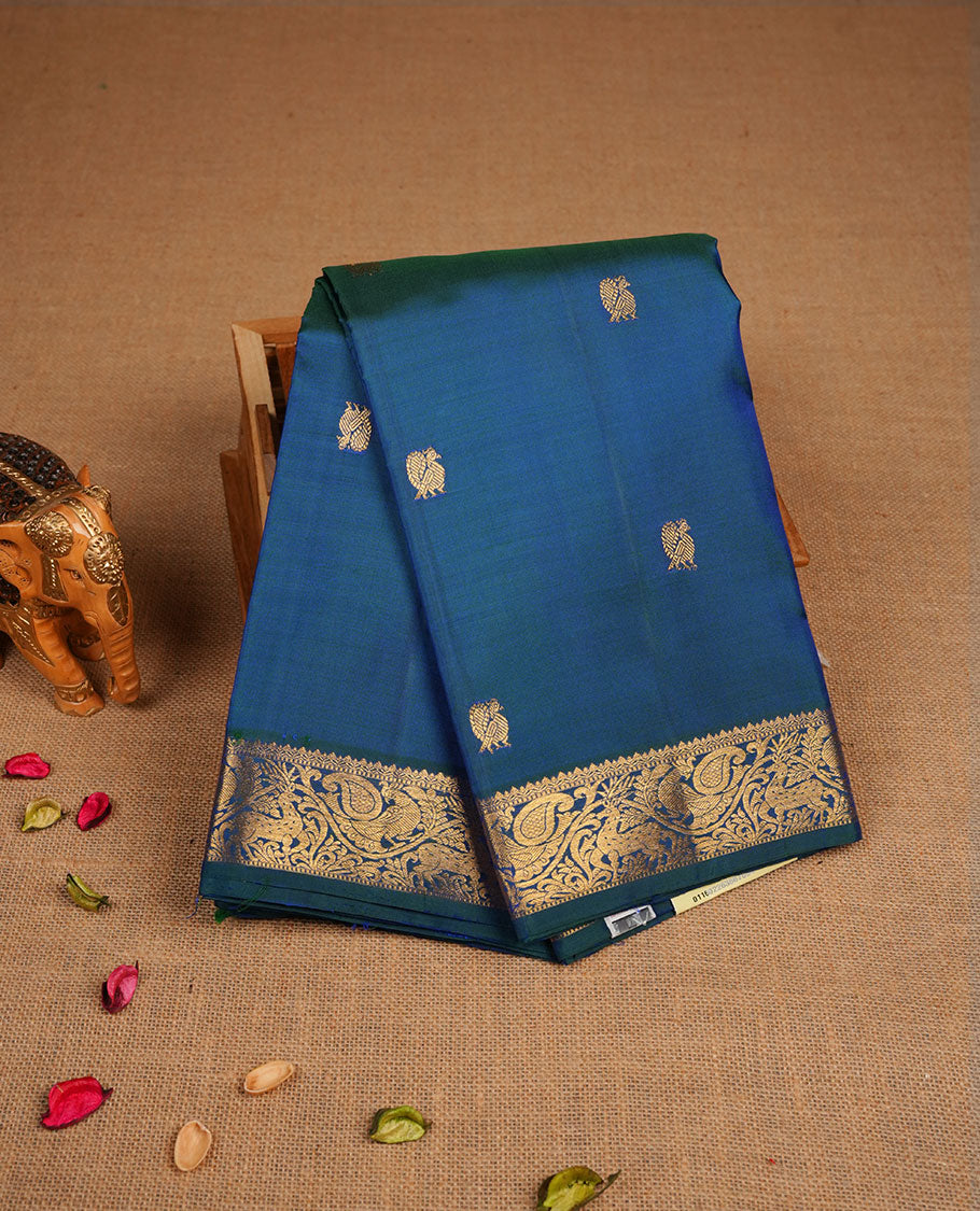 Peacock blue pure traditional Kancheepuram silk saree adorned with gold zari peacock motifs across the body, featuring elegant traditional borders with animal motifs, beautifully paired with a matching blouse piece.
