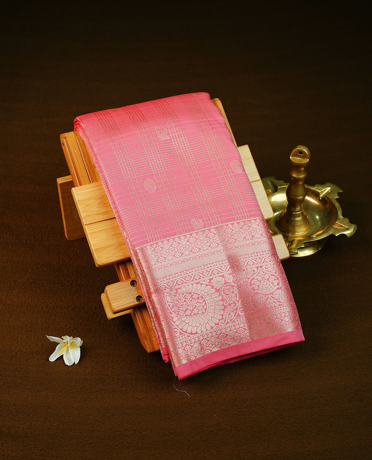 Pink colour semi wedding saree featuring light gold zari strips with peacock and chakra motifs across the body, complemented by contrast self colour traditional border. Comes with a matching blouse piece.