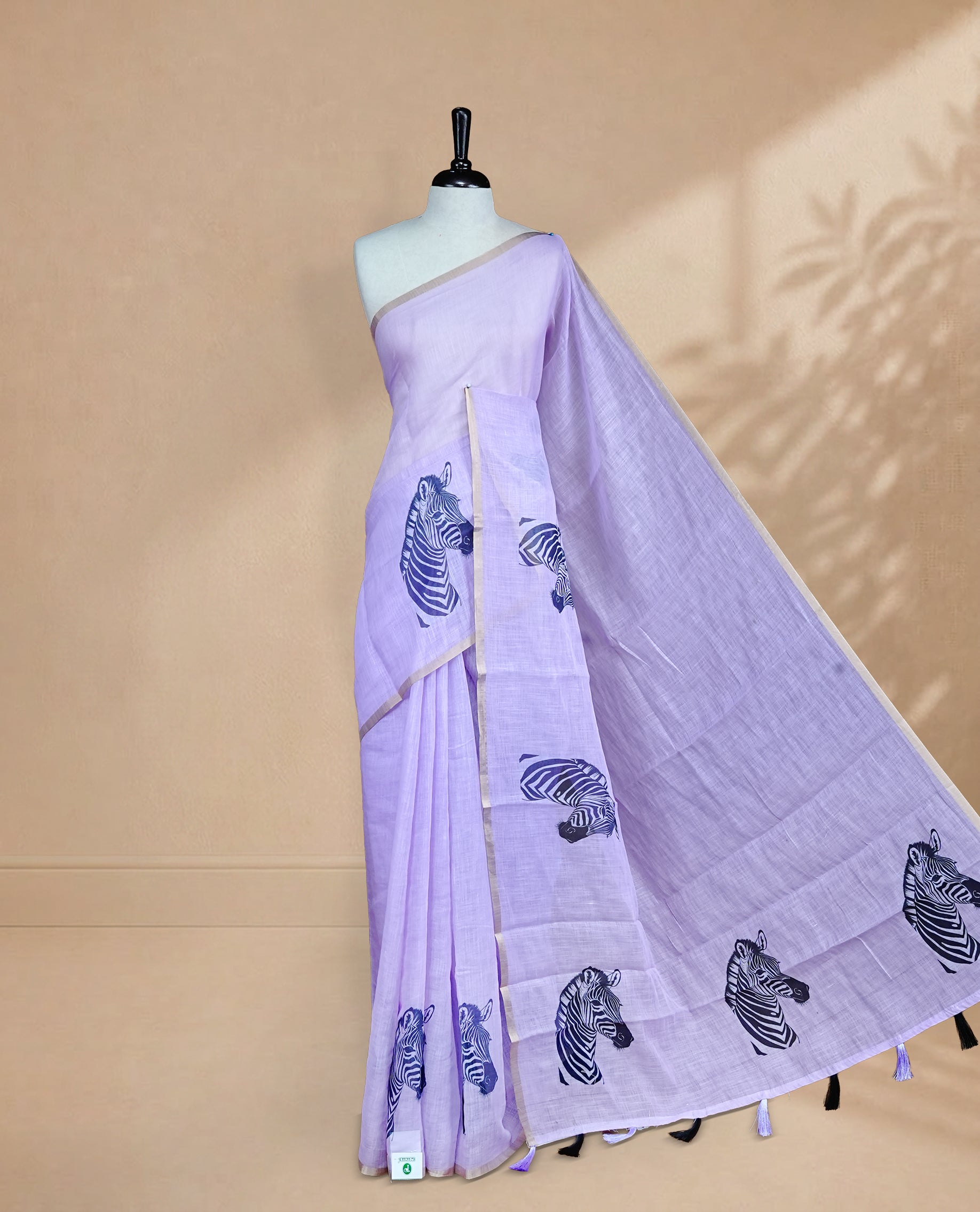 Lavender semi linen saree featuring an elegant zebra print all over the body, highlighted with a delicate tissue border and paired with a matching blouse piece.