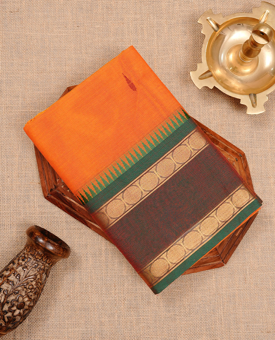 Orange colour chettinad cotton saree featuring motifs on body, complemented by Green colour with zari border, paired with matching blouse piece.