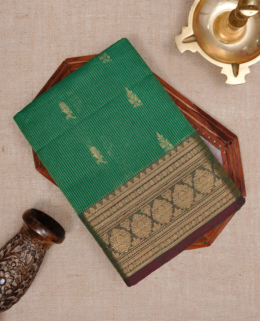 Green colour chettinad cotton saree featuring gold zari stripes & motifs on body, complemented by Contrast Maroon colour with zari border, paired with matching blouse piece.