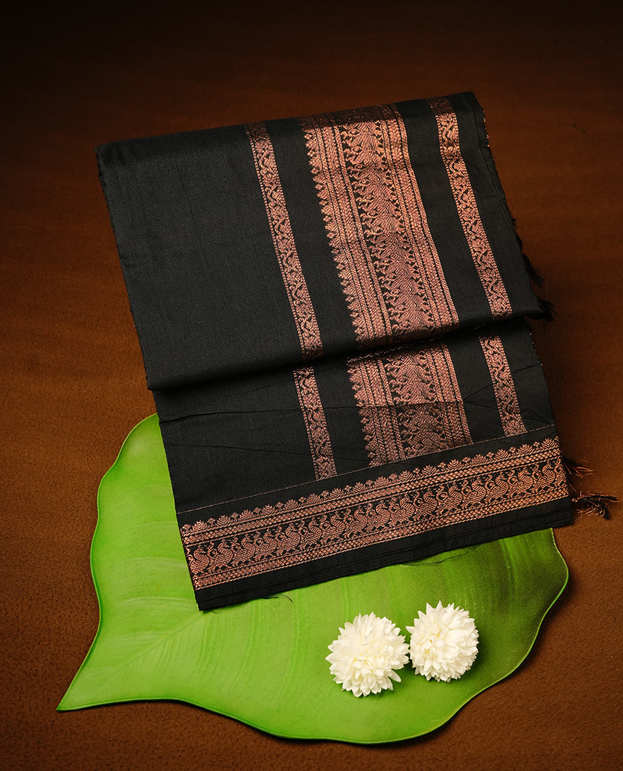 Black colour kalyani cotton saree featuring gold zari motifs on body, highlighting self colour with Antique gold zari border, paired with matching blouse piece.