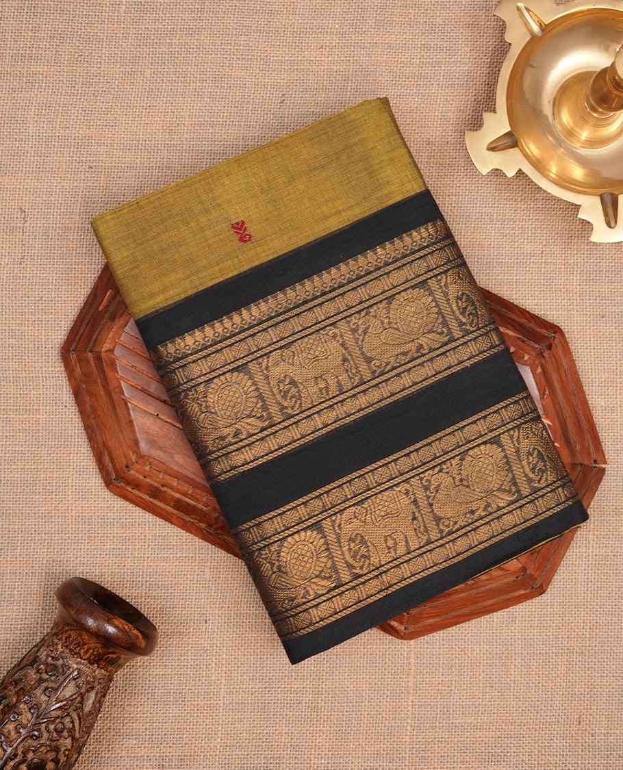 Olive colour chettinad saree featuring gold zari motifs on body, complemented by contrast black colour with traditional border, paired with matching blouse piece.