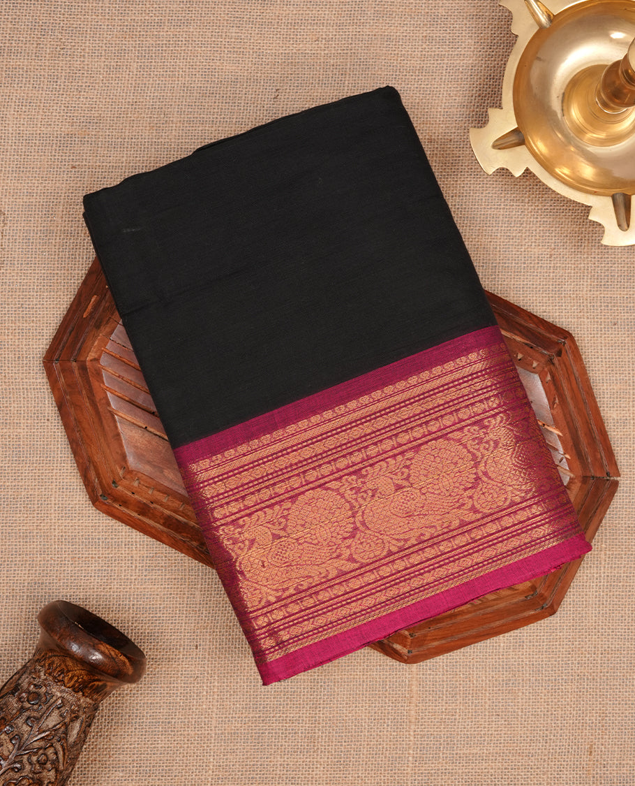 Black colour chettinad cotton saree featuring elegant plain body, complemented by contrast magenta colour with gold zari border, paired with matching blouse piece.
