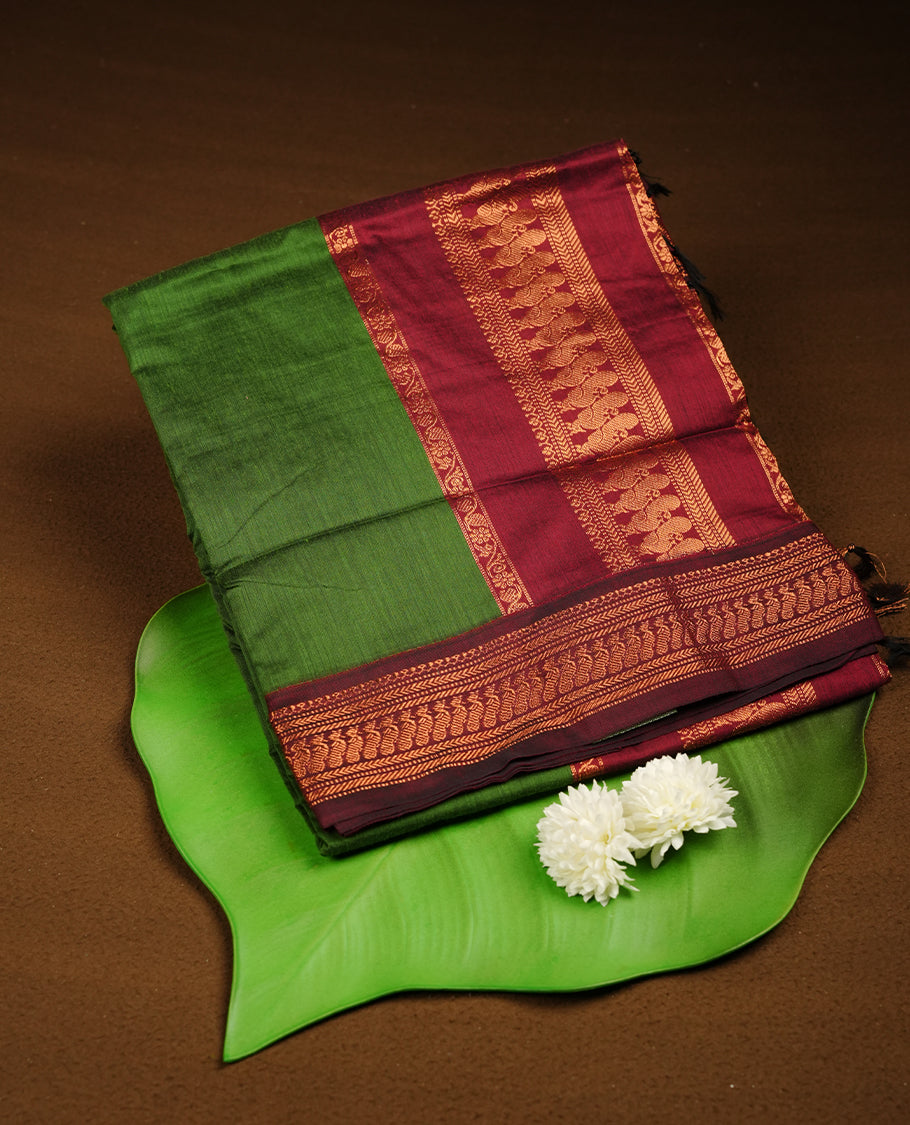 Green colour Kalyani cotton saree featuring a plain elegant body, complemented by a deep maroon border and traditional woven pallu, paired with a matching blouse.