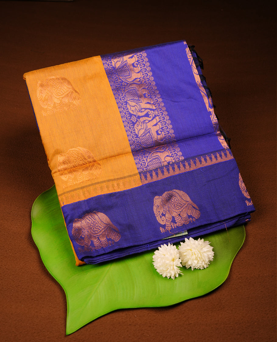 Mustard colour mixed Kalyani cotton saree with subtle zari motifs, royal blue zari border and elephant motif pallu, paired with a matching blouse.