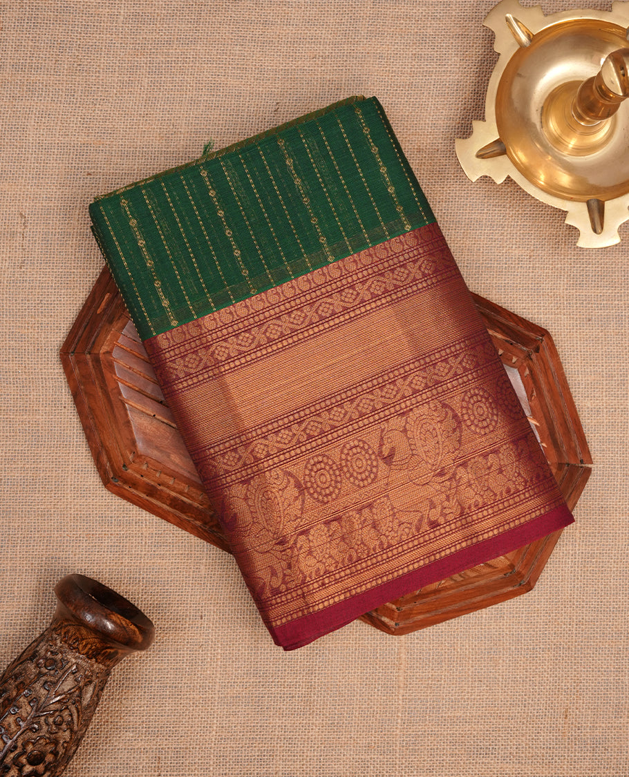Green colour chettinad saree featuring gold zari stripes on body, complemented by contrast maroon colour with traditional border, paired with matching blouse piece.