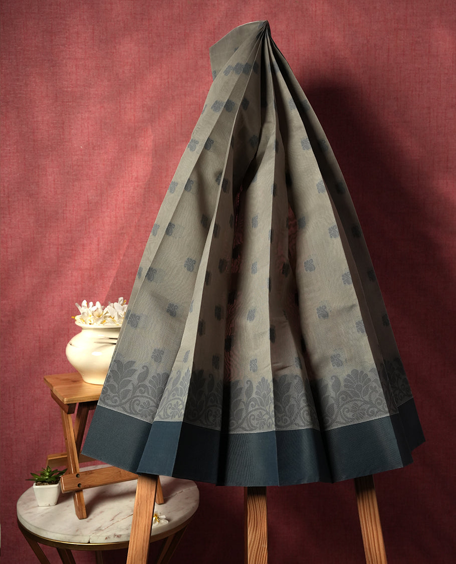 Grey colour silk cotton saree featuring elegant floral zari motifs on the body, complemented by a rich contrast border and pallu with traditional woven detailing & Comes with a matching blouse piece.