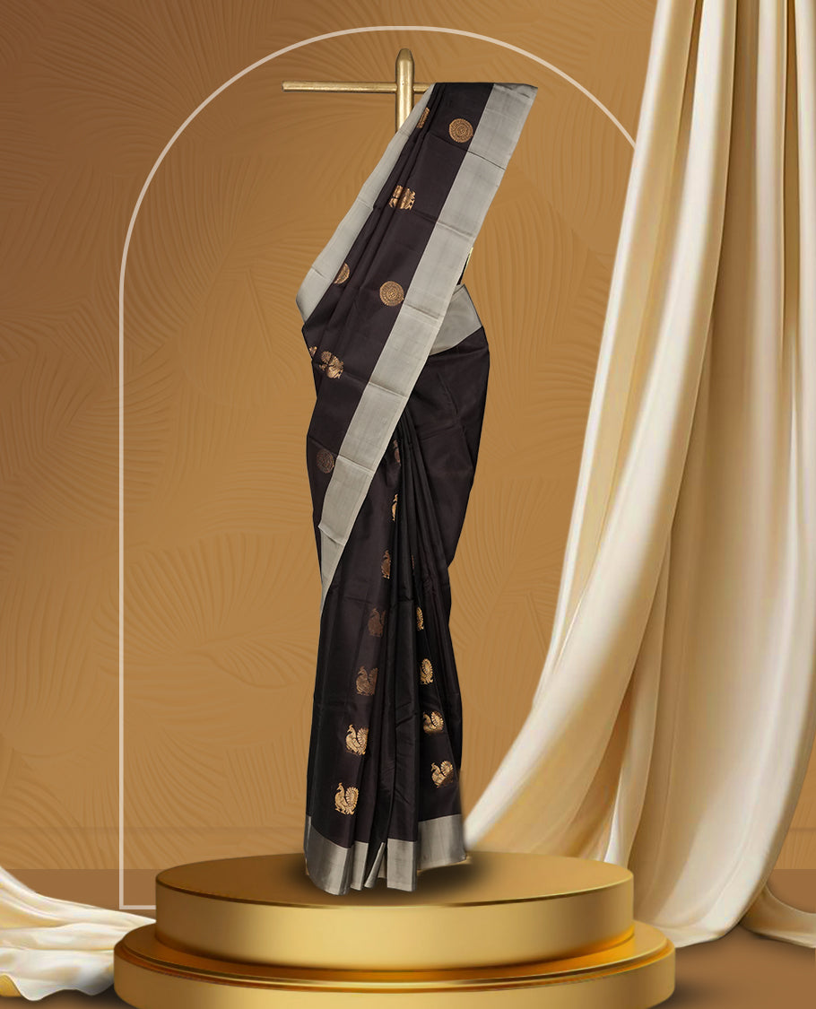 Dark brown colour soft silk saree embellished with graceful golden buttas, enhanced by an elegant silver grey border and pallu & Paired with a matching blouse.