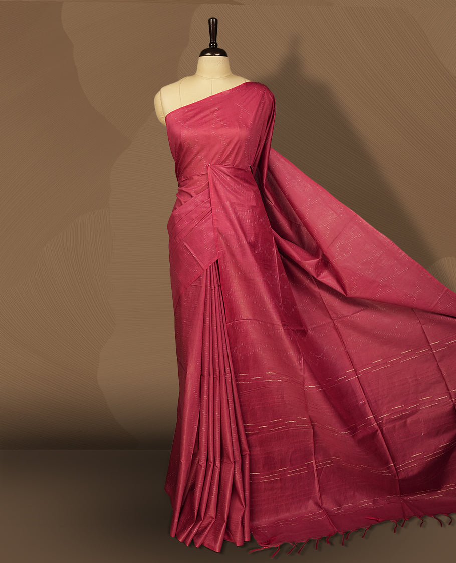 Crimson red colour semi jute saree featuring subtle linear woven motifs across the body, Enhanced with a finely crafted pallu and sleek border & Comes with a matching blouse piece for a complete look.