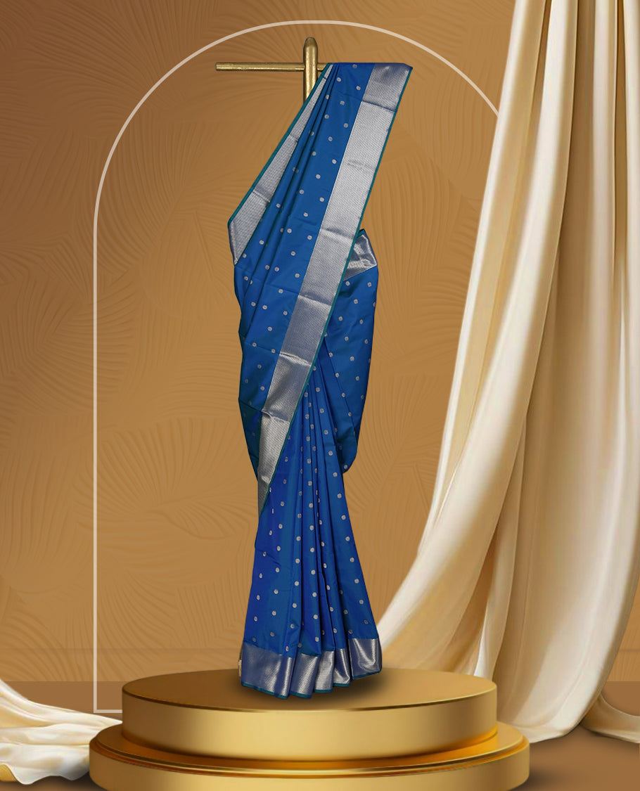Royal blue colour soft silk saree adorned with small silver buttas, enhanced by a shimmering silver zari border and pallu with delicate motifs & paired with a matching blouse.