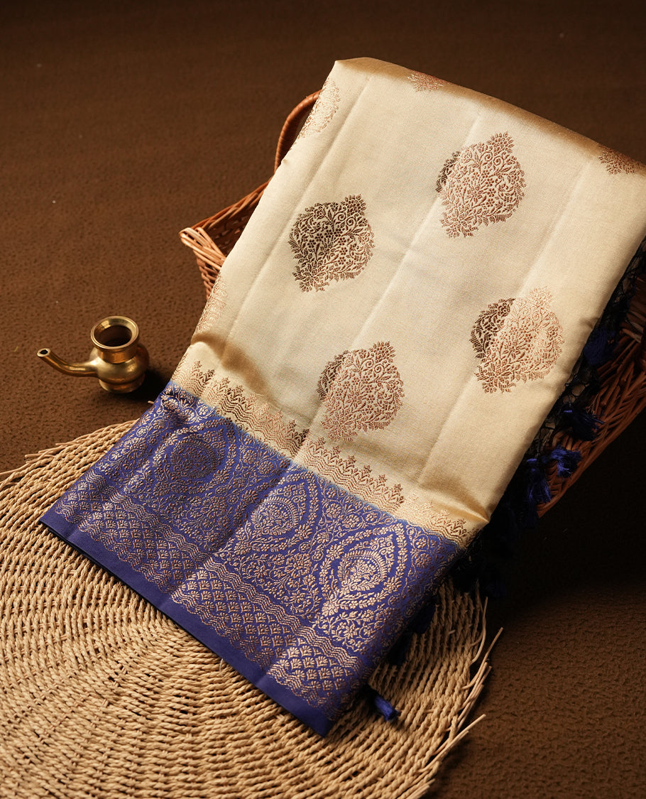 Cream beige Banaras soft silk saree with gold zari oval motifs on body, with contrast Blue colour floral pattern on pallu, border, and Matching blouse.