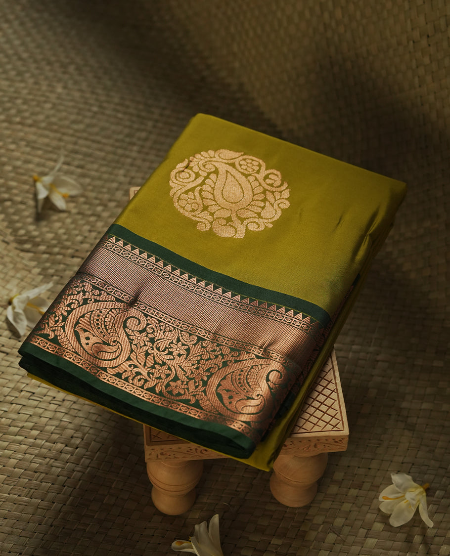 Mustard green colour Semi Silk Saree with gold zari motifs on the body, paired with a contrast Dark green colour pallu with copper zari traditioal border, and a matching blouse piece.