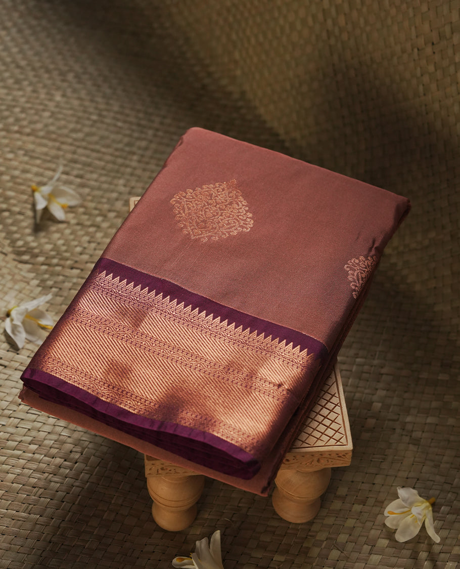 Dusty Rose colour Semi Silk Saree with copper zari motifs on the body, paired with a contrast Dark purple colour pallu with copper zari traditioal border, and a matching blouse piece.