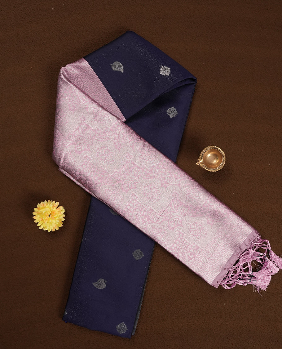 Navy blue colour semi silk saree adorned with subtle silver zari motifs on the body, complemented by contrasted a pastel light pink pallu intricately woven with rich floral patterns border and pallu, and paired with a matching blouse
