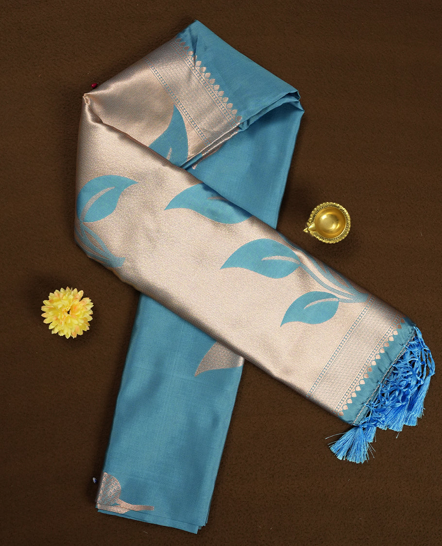 Sky blue colour semi silk saree adorned with elegant floral motifs on the body, complemented by a shimmering golden zari-woven pallu and border, and paired with a matching blouse