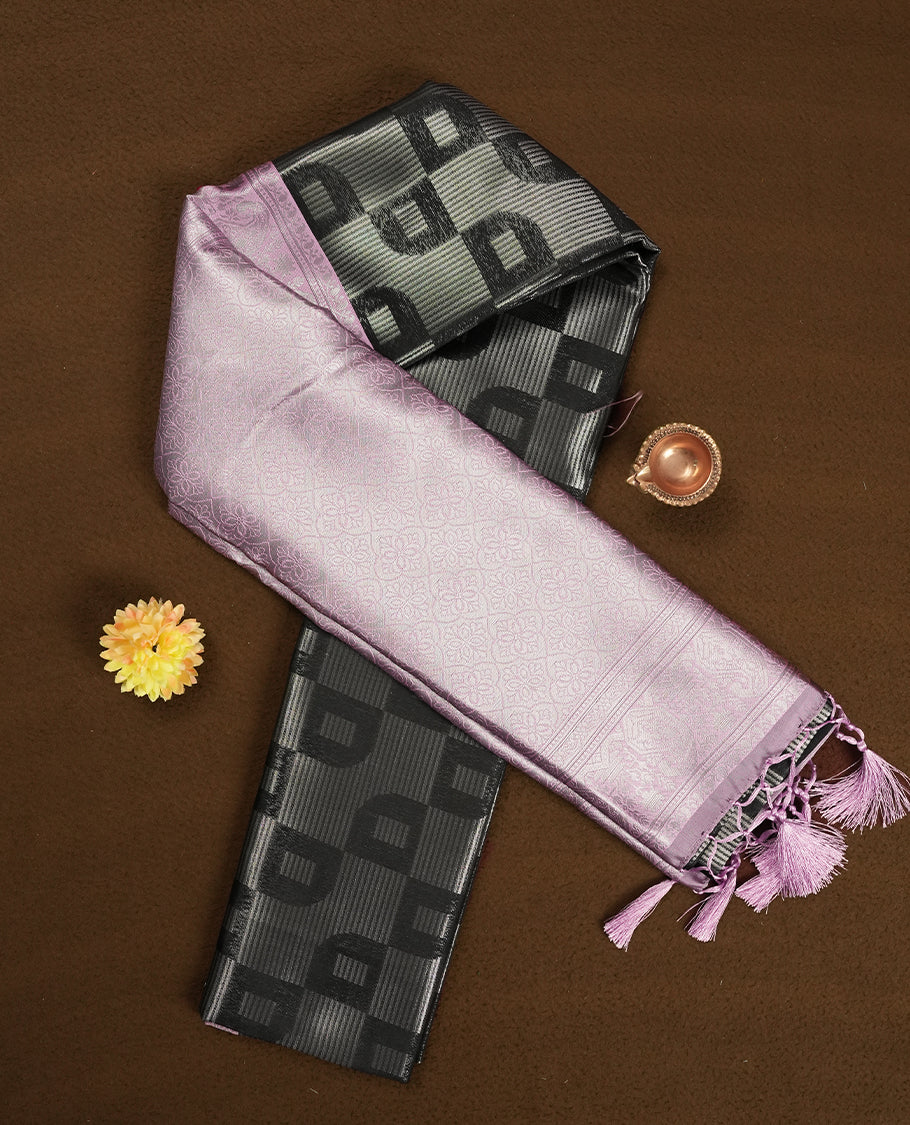 Black colour semi silk saree adorned with silver zari designs on the body, complemented by a contrasting light pink border and pallu, and paired with a matching blouse piece