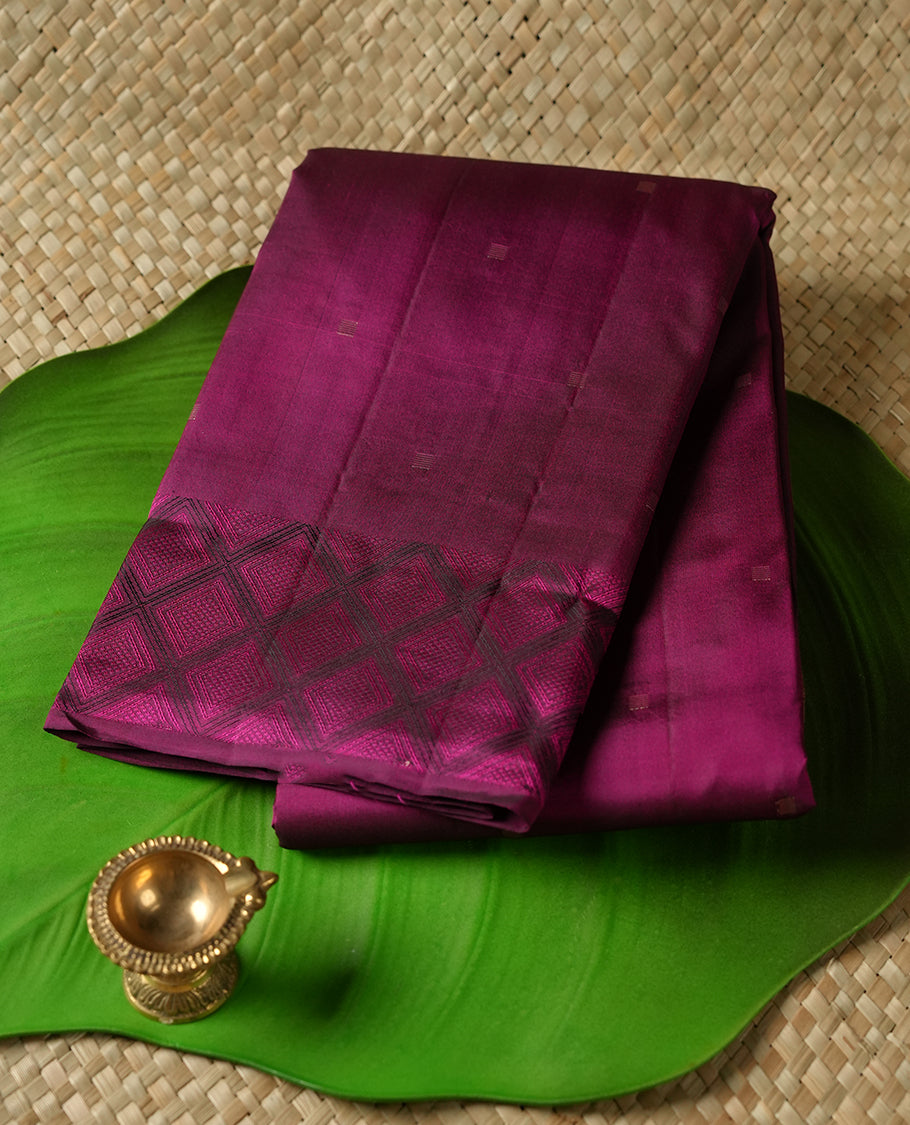 Deep violet colour Vasundhara silk saree adorned with all-over gold square motifs on the body, complemented by a Black & pink colour zigzag border and paired with a matching blouse piece.