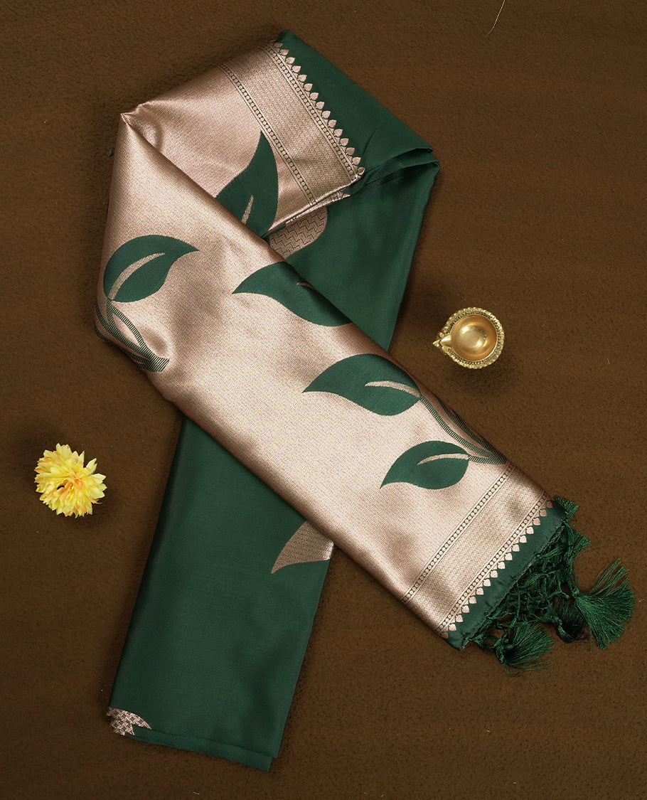 Dark green colour semi silk saree adorned with elegant floral motifs on the body, complemented by a shimmering golden zari-woven pallu and border, and paired with a matching blouse