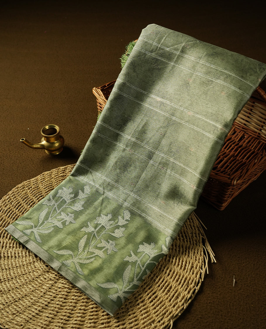 Sage green colour semi tussar saree adorned with Cream strip printed pattern across the body and Floral pattern contrast fern green colour on border, paired with a matching blouse.