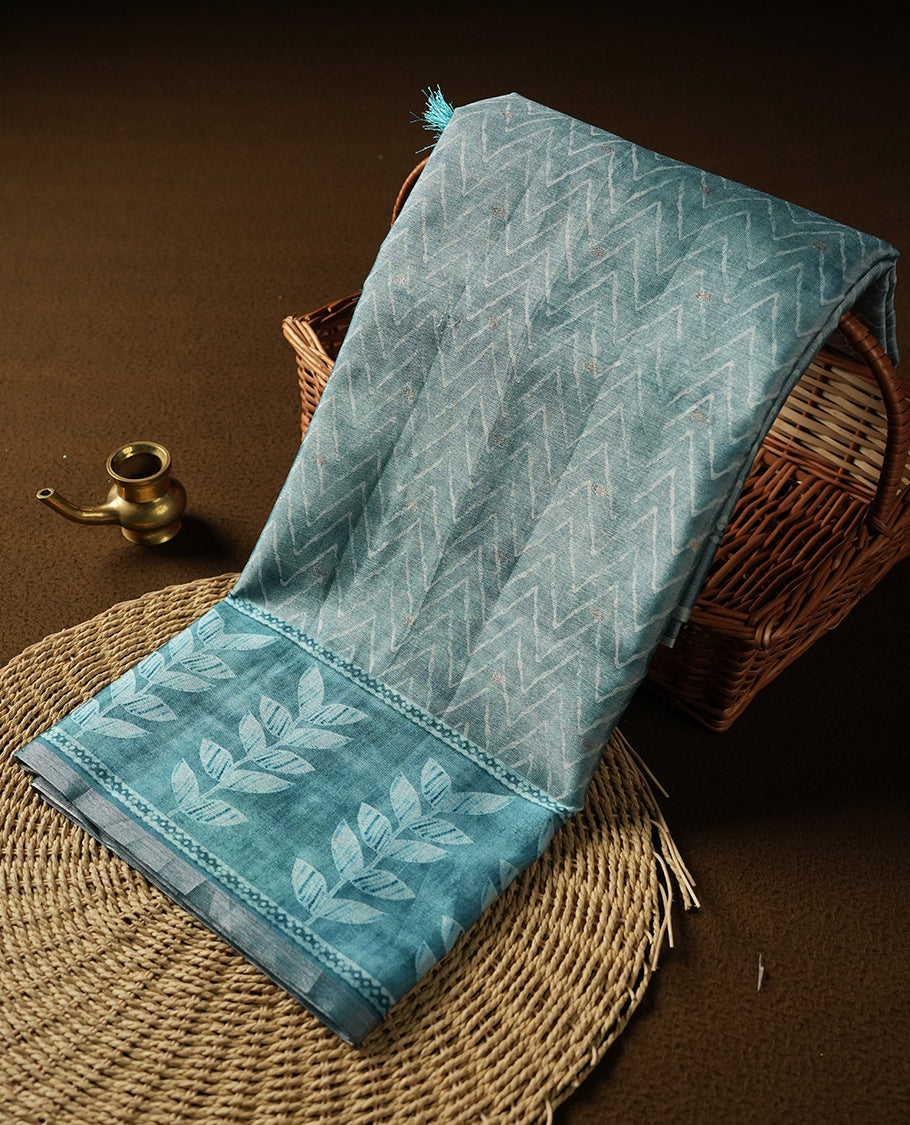 Aqua blue colour semi tussar saree adorned with Cream Zigzag printed pattern across the body and Leaf pattern on contrast aqua blue colour border, paired with a matching blouse.