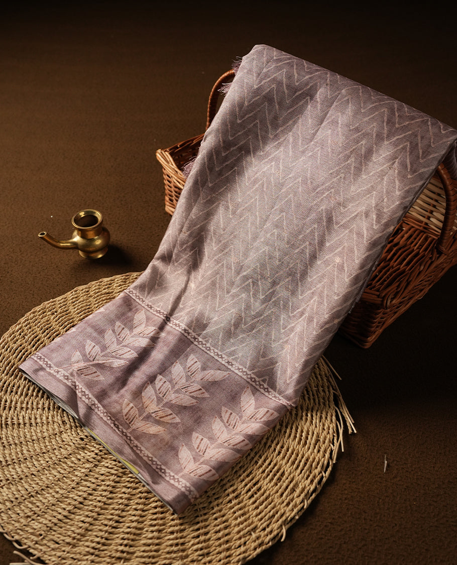 Pink copper colour semi tussar saree adorned with Cream Zigzag printed pattern across the body and Leaf pattern on border, paired with a matching blouse.